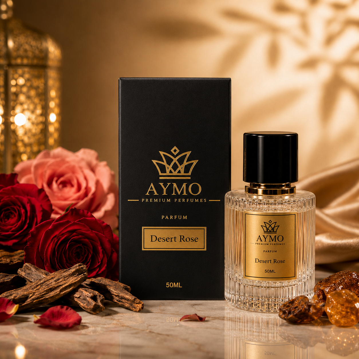 A bottle of Aymo Desert Rose perfume and its black packaging box, styled with red roses, dried spices, and amber pieces on a marble surface with a warm golden background.